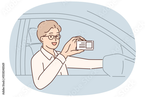 Man driving car demonstrates driver license giving right to work in taxi company