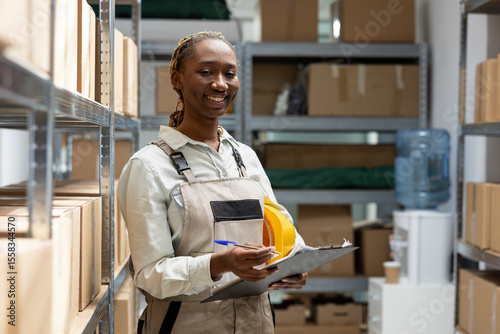African american woman sorting retail boxes for dispatch from depot racks, manual work job. Business operations focus on logistics, supply chain efficiency and shipment readiness.