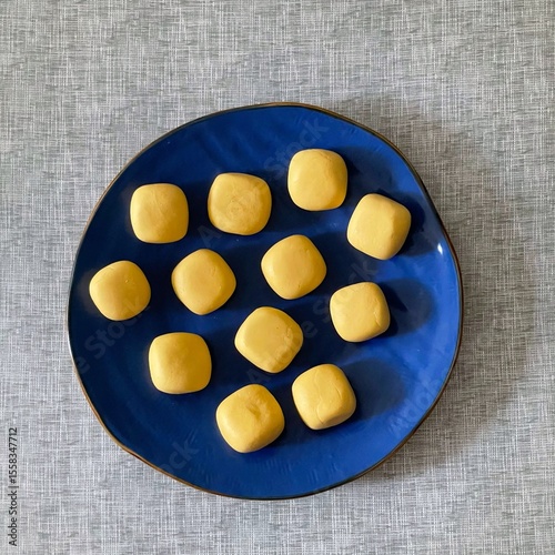 Fototapet Freshly shaped pumpkin dough balls lie on a cobalt - blue plate, waiting to rise for baking