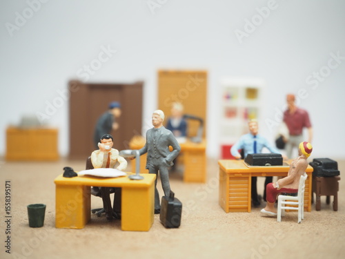 Mini toy of action figure at table with blurred background. Diorama photography concept design. Minifigure office workers casually interacting on office, symbolic of quiet quitting culture.