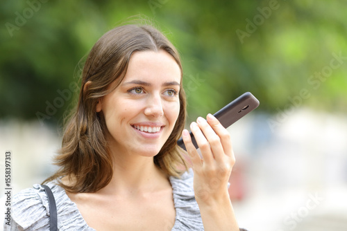 Happy woman dictating message on phone