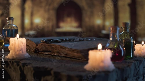 Scene from magical ritual: potion bottles, worn pages of ancient tome and hand forged magic wand lit by warm candle flames, surrounded by stone walls and mystical shadows in old castle.