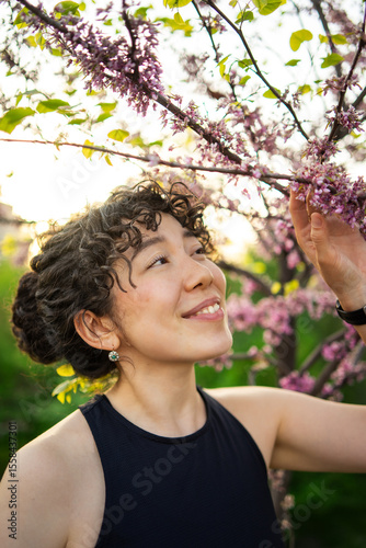 Woman appreciating cherry blossoms in garden