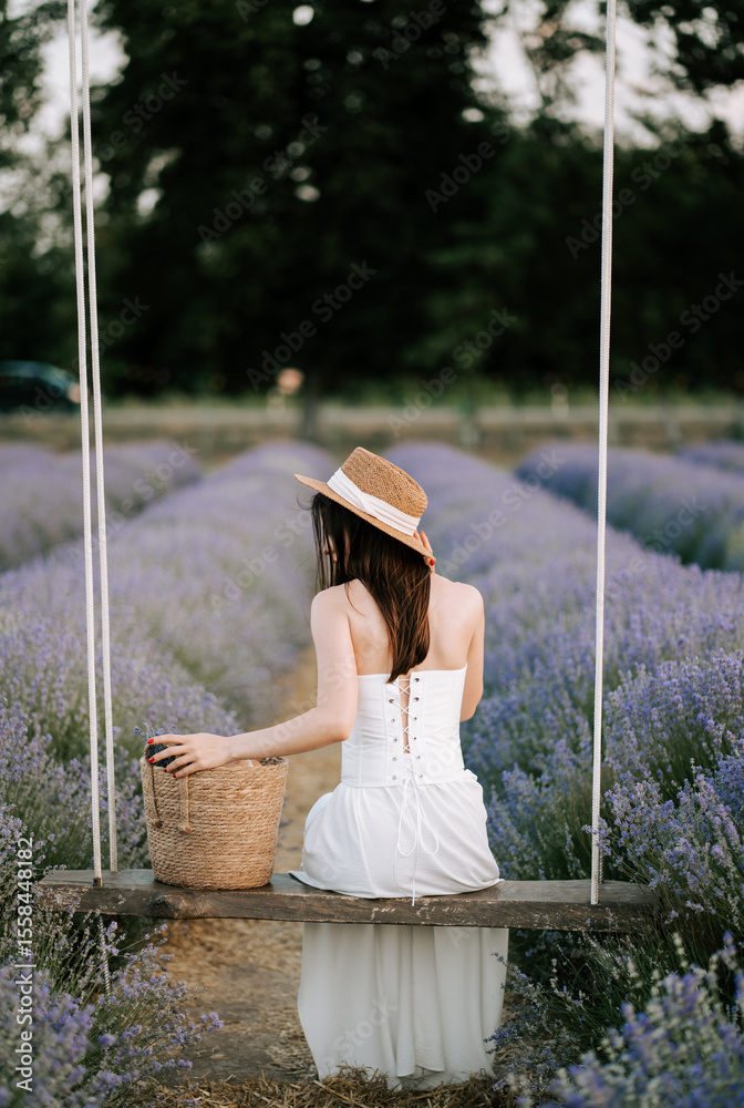 Obraz premium Woman on a swing in a lavender field during the golden hour of evening light