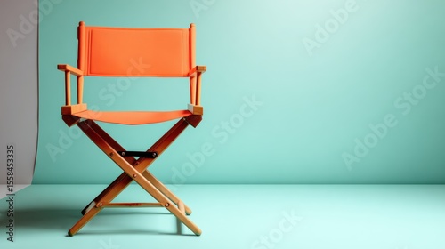 Bright orange folding chair open and facing camera on a pale pastel green backdrop photo