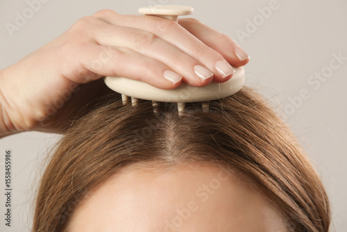 Girl doing herself a head massage using a scalp massager, stimulating hair growth, microcirculation, help to distribute natural oils more evenly across the scalp