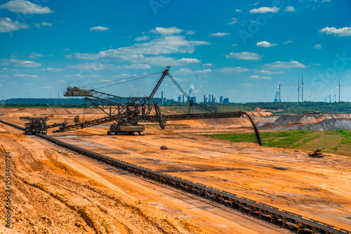 Stacker and conveyor belt at Garzweiler I opencast mine in Germany with coal-fired power plants in the background