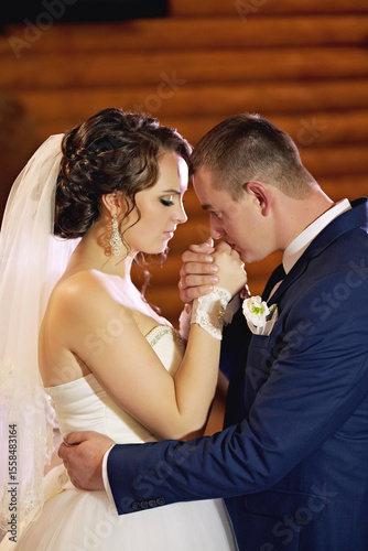 A bride and groom are embracing each other, with the bride wearing a white dress and the groom wearing a blue suit
