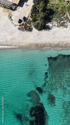 Vue verticale de la plage de Saint Cyprien en Corse, révélant le sable blanc, l’eau turquoise et les fonds marins sombres.