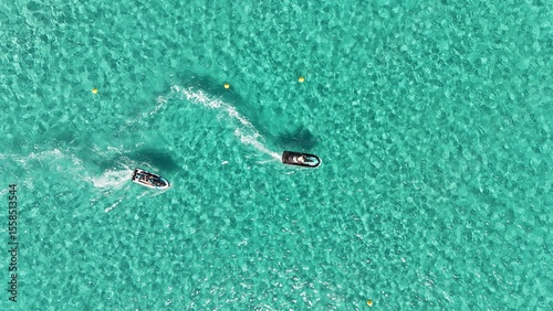 Deux jets ski vus du ciel dans les eaux claires de la baie de Santa Giulia, traçant des sillages blancs sur fond turquoise.