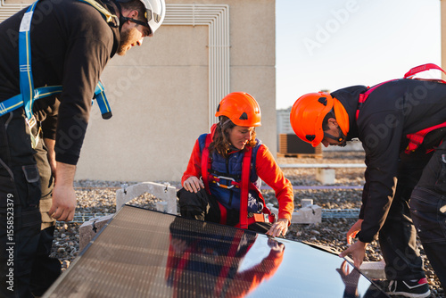 Workers installing rooftop solar panels in daylight