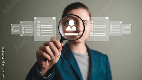 Recruitment Process: Person using magnifying glass to examine a candidate profile on a digital screen, symbolizing careful selection and detail-oriented approach to recruitment. 
