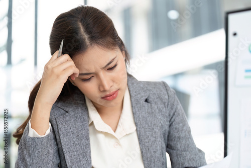 Stressed Businesswoman Reviewing Financial Documents in Office