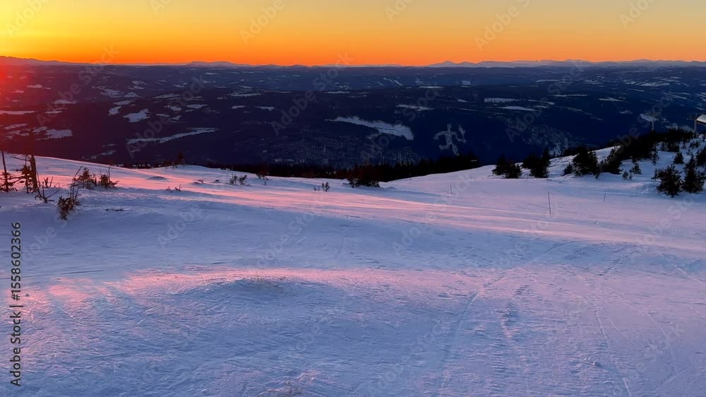 Olympic torch man on top of Øyer mountain Lillehammer Hafjell Alpine resort Norway Norge chairlift groomed trail ski runs golden hour vibrant sunset winter terrain landscape breeze frigid pan left