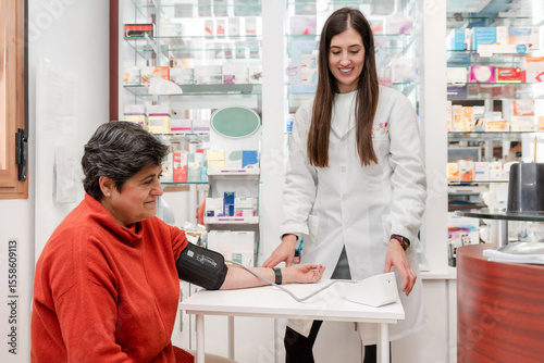 Smiling female pharmacist measuring blood pressure of senior woman customer in a pharmacy