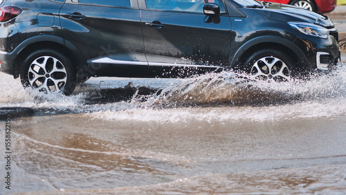 Suv navigating deep water puddle, spraying liquid forcefully during rainy conditions, demonstrating challenging road surface after storm