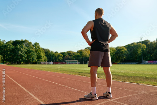 Valokuva Fit man standing on stadium track looking ahead with hands on hips