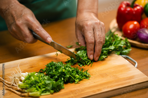 Fotografie Asian man's hands chopping coriander in the kitchen