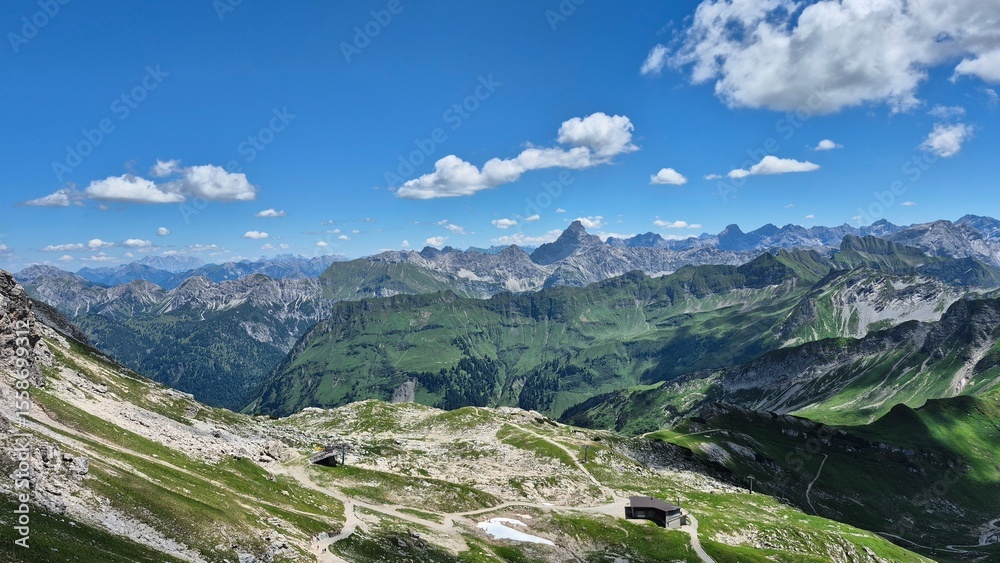 Fototapeta premium Oberstdorf Allgäuer Hochalpen, breathtaking panoramic view of alpine mountains under a clear blue sky with vibrant greenery and scattered clouds on a sunny day, from top of cable car station 