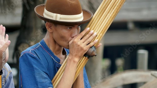 Young Asian man wearing a cowboy hat playing the Khaen, a traditional musical instrument of the Isan region of Thailand. video 4K