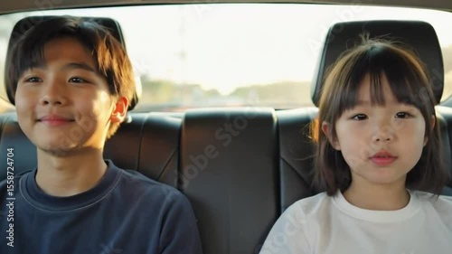 Two children smiling while sitting in the backseat of a car  