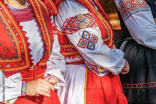 Colorful traditional Eastern European folk costumes with intricate embroidery are worn during a lively outdoor cultural festival.
