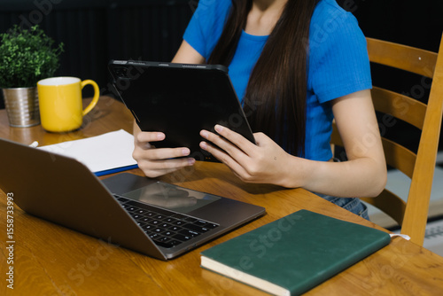 Woman using digital tablet at home, enjoying remote work or online entertainment. Cozy lifestyle, modern tech habits, and casual home environment