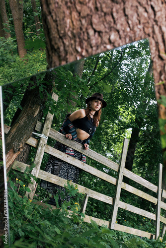  A girl's outfit styled after the indigenous peoples of the world. International Day of the Indigenous Peoples of the World. A photo with a mirror against a nature background.