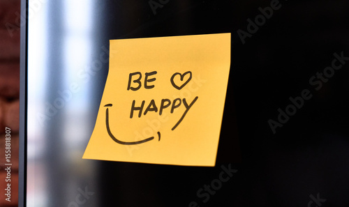 A yellow sticky note with a cheerful message to be happy