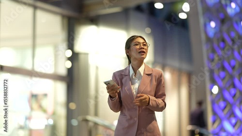 Young Asian woman standing taking notes professional working indoors with focus and confidence, managing digital work and business communication efficiently.