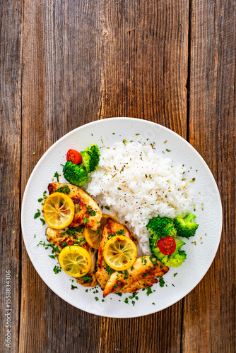 Lemon chicken escalopes with rice on wooden table