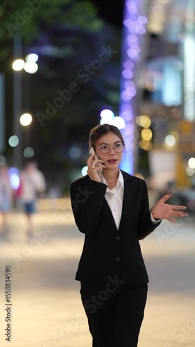 Young Asian woman standing taking notes professional working indoors with focus and confidence, managing digital work and business communication efficiently.