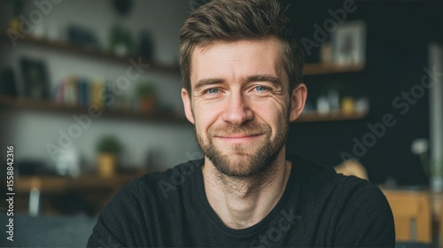 portrait of adult European softly smiling man is 30 years old wearing black T-shirt at living room background