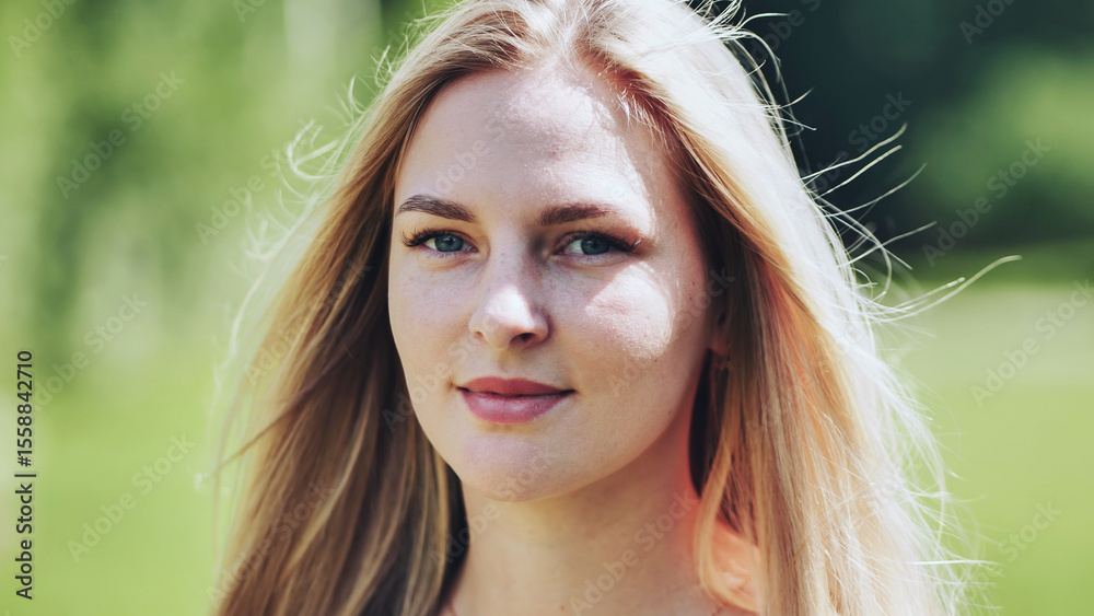 Naklejka premium Freckled blonde relaxing outdoors, beaming with sunlight warming her face