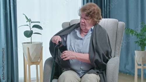 Senior woman with tremor trying to get up from armchair and walk, problem with health after retirement