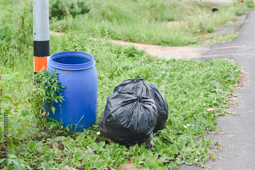 Close-up of a black bag next to a blue trash can.