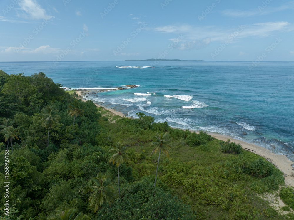 Obraz premium An aerial view of a tropical island with white sand beaches and turquoise waters. Waves crashing on a white sandy tropical beach