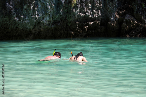 Fototapeta Naklejka Na Ścianę i Meble -  Snorkeling in a sea, couple swimming in diving masks in water. Beach vacation in summer