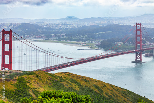 Wallpaper Mural Panoramic view of the Golden Gate Bridge spanning San Francisco Bay with cityscape, lush hills, and boats, captured from a high vantage point on a cloudy spring day Torontodigital.ca