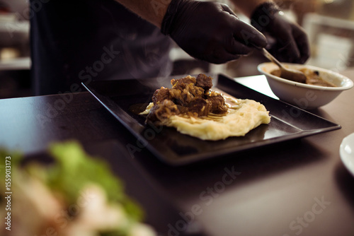 Chef plating gourmet meal with precision in fine dining restaurant