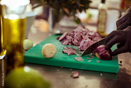 Chef chopping onions on cutting board in professional kitchen