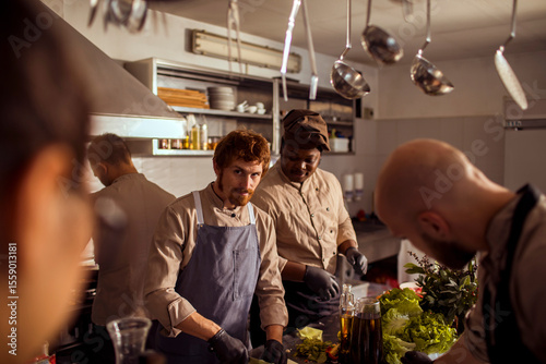 Professional chefs preparing food together in a busy restaurant kitchen