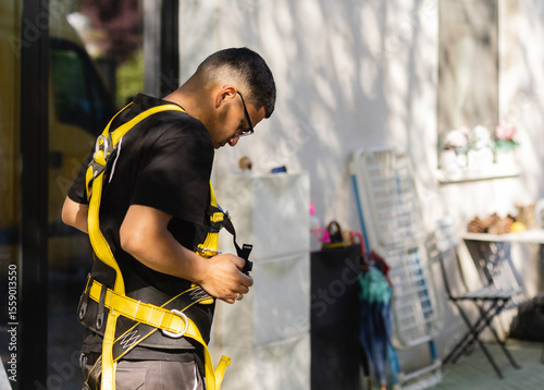 Obraz na plátně Construction worker adjusting safety harness before climbing