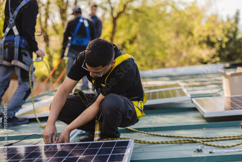 Workers installing solar panels on rooftop for green energy production