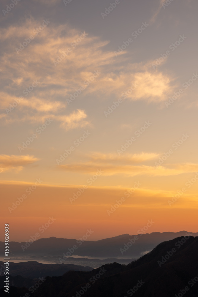 Fototapeta premium 埼玉県秩父市の三峰神社から望む朝焼けの山並みと空の風景。2022年11月19日撮影。晩秋の澄んだ空気の中、赤く染まった空と重なる山々が幻想的な絶景を描き、旅行や自然風景、癒しをテーマに最適です。