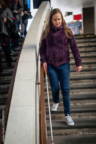 A visually impaired woman with white cane coming down the stairs outside