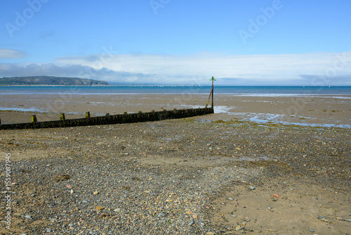 A beach with a wooden fence and a green post