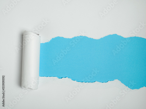 A piece of white paper is torn, revealing a vibrant blue background underneath.