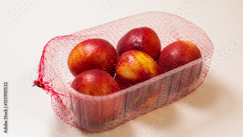 Summertime nectarines swathed in rustic mesh, evoking Augusts bounty, Midsummers Eve feasting, and tactile sensory indulgence