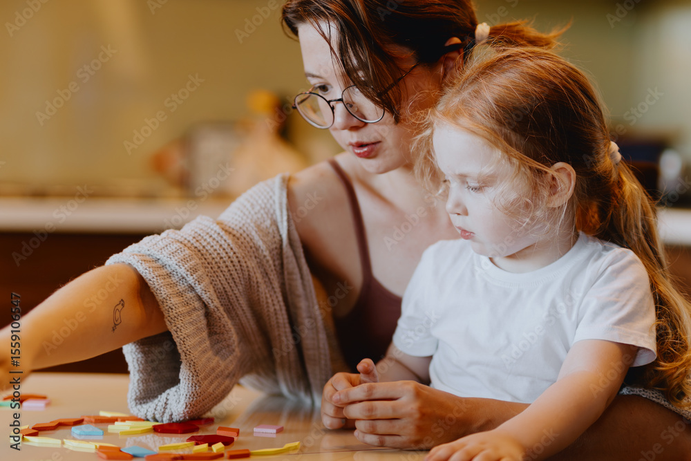 Fototapeta premium A sweet 3-year-old girl plays board games with her mom, sharing precious moments of love, learning and bonding. Perfect for family and early education content